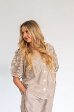 Load image into Gallery viewer, Woman wearing a striped outfit standing against a white wall.
