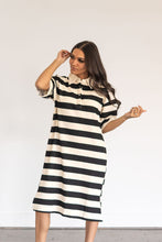 Load image into Gallery viewer, Woman wearing a black and white striped dress with black boots on a plain background
